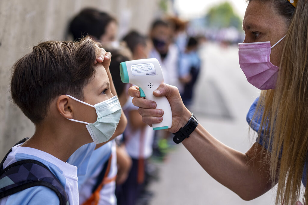 Una maestra con mascarilla para protegerse contra la propagación del coronavirus revisa la temperatura de un alumno en la escuela Maestro Padilla, al inicio del año escolar, el martes 7 de septiembre de 2021, en Madrid, España. (AP)