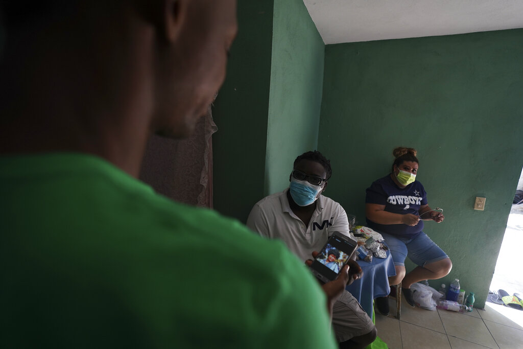 Mensah Montant, centro, y su esposa Virginia Salazar visitan a un migrante haitiano en un departamento en Ciudad Acuña, el viernes 24 de septiembre de 2021. (AP)