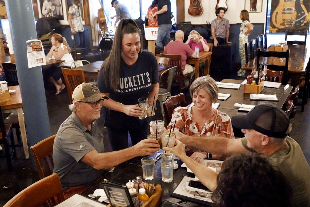 Macy Norman (centro) observa un brindis mientras atiende una mesa del Puckett's Grocery and Restaurant de Nashville, Tennessee, el 10 de septiembre del 2021. (AP)