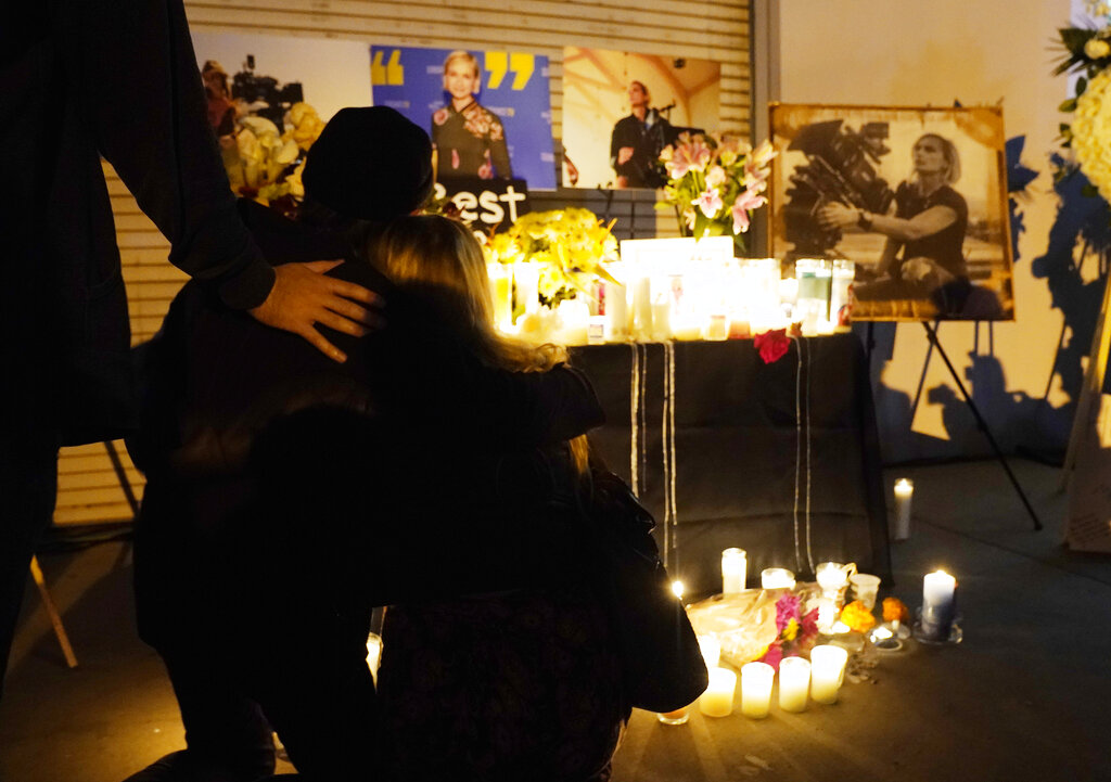 Asistentes se abrazan en una vigilia por la fallecida directora de fotografía Halyna Hutchins, representada en fotografías al fondo, el domingo 24 de octubre de 2021, en Burbank, California. (AP)