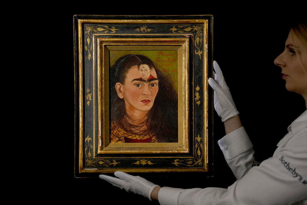 Una miembro del personal sostiene el autorretrato de 1949 Diego y yo de Frida Kahlo en la casa de subastas Sotheby's en Londres, el 21 de octubre de 2021. La obra se vendió el martes en Nueva York por 34.9 millones de dólares. (AP)