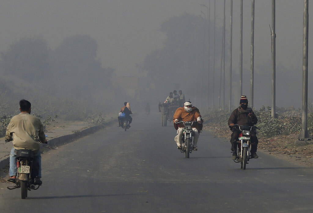 Motociclistas conducen en un camino cubierto de smog en el área de Lahore, Pakistán, el lunes 22 de noviembre de 2021. (AP)