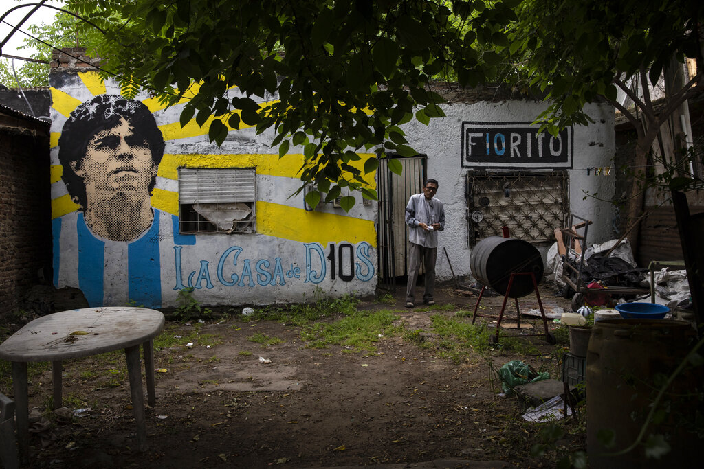El dueño de la casa donde el extinto astro del fútbol Diego Maradona creció, de pie frente a un mural con la fase La Casa de Dios, en el barrio de Fiorito, el jueves 25 de noviembre de 2021, en Buenos Aires, Argentina, al cumplirse el primer año de su fallecimiento. (AP)