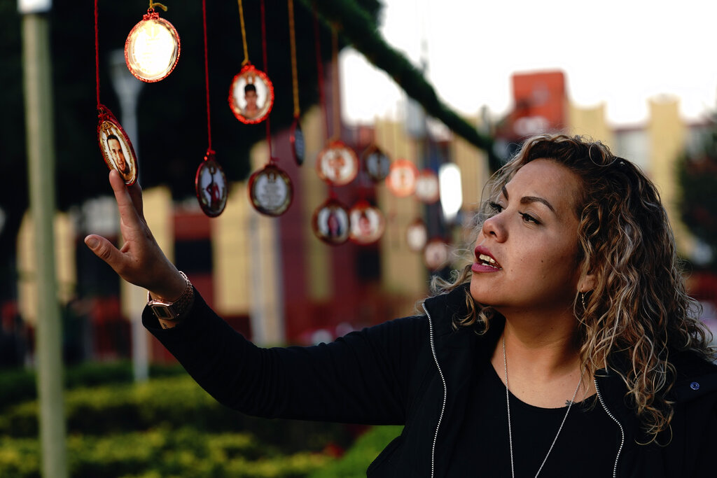 Una mujer toca un adorno navideño con la imagen de un ser querido desaparecido en el Jardín Memorial colocado por parientes de las víctimas en un parque ante el edificio de gobierno de la ciudad de Iztacalco, en Ciudad de México, el martes 14 de diciembre de 2021. (AP)