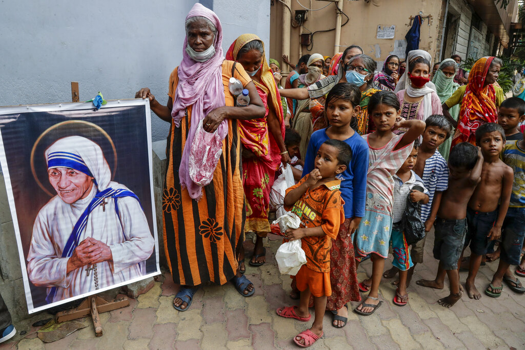 un grupo de personas sin hogar se reúne junto a un retrato de Santa Teresa, la fundadora de Misioneras de la Caridad, para recibir comida, en el exterior de su sede en Calcuta, India, el 26 de agosto de 2021. (AP)
