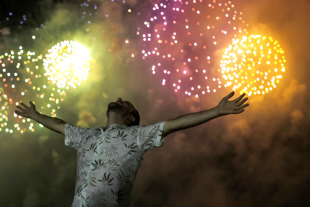 Un hombre celebra el inicio del año nuevo bajo el cielo iluminado por fuegos artificiales, en la playa de Copacabana, en Río de Janeiro, Brasil, el 1 de enero de 2022. (AP)