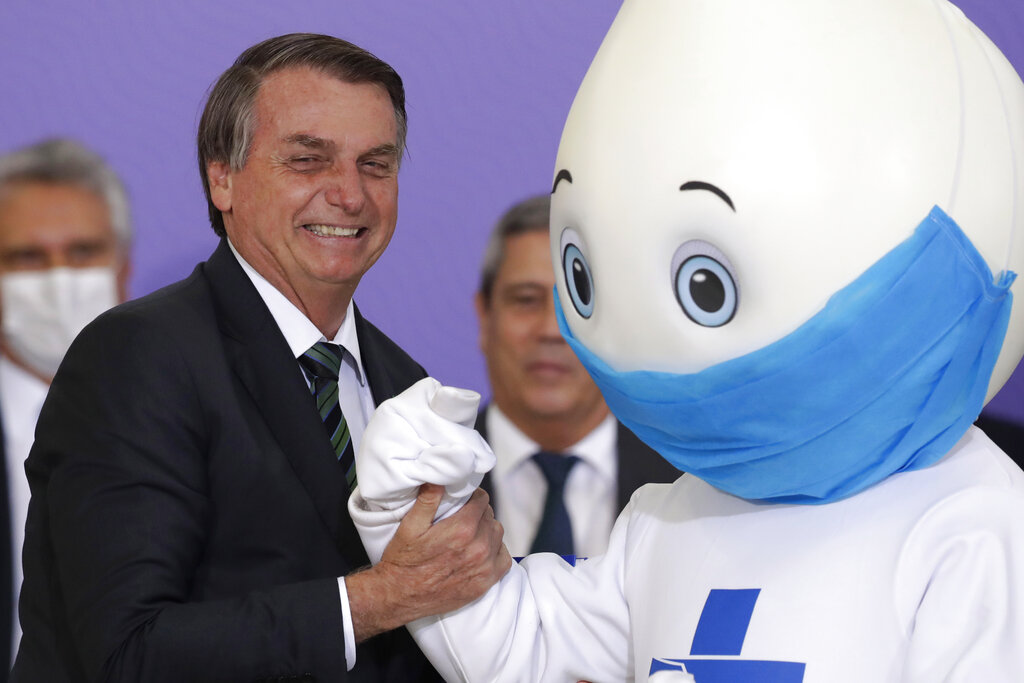 El presidente de Brasil Jair Bolsonaro posa para una foto con la mascota de la campaña de vacunación del país contra el COVID-19. (AP)