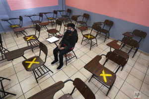 UN estudiante se sienta solo en el primer día del regreso a clases presenciales en la secundaria República de Argentina, en la Ciudad de México. (AP)