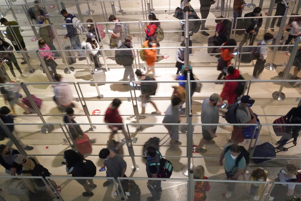 Viajeros con mascarillas como medida de prevención contra el contagio de coronavirus hacen fila para una revisión de seguridad en el aeropuerto Love Field, en Dallas, el viernes 31 de diciembre de 2021. (AP)
