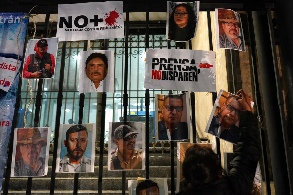 Una mujer coloca fotos de reporteros muertos durante una protesta nacional por el asesinato de Lourdes Maldonado y del fotógrafo independiente Margarito Martínez, en la Ciudad de México, el 25 de enero de 2022. (AP)