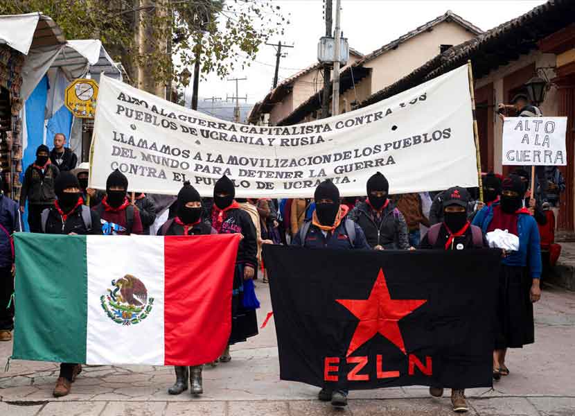 Miembros del EZLN sostienen una bandera mexicana y una de su movimiento durante la protesta. / Foto: AP