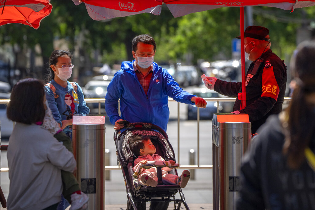 Un guardia de seguridad toma la temperatura de visitantes que entran a un parque público en Beijing el 30 de abril del 2022. (AP)
