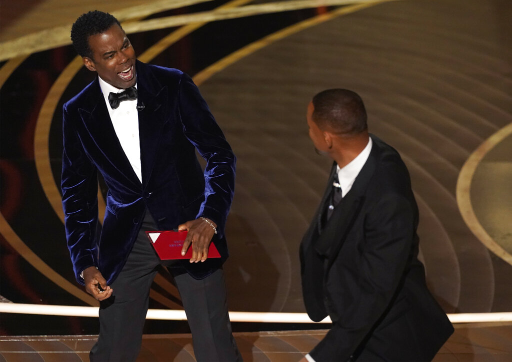 El presentador Chris Rock, izquierda, reacciona tras ser golpeado en el escenario por Will Smith al presentar el premio a mejor documental en los Oscar el domingo 27 de marzo de 2022, en el Teatro Dolby en Los Angeles. (Foto AP/Chris Pizzello)
