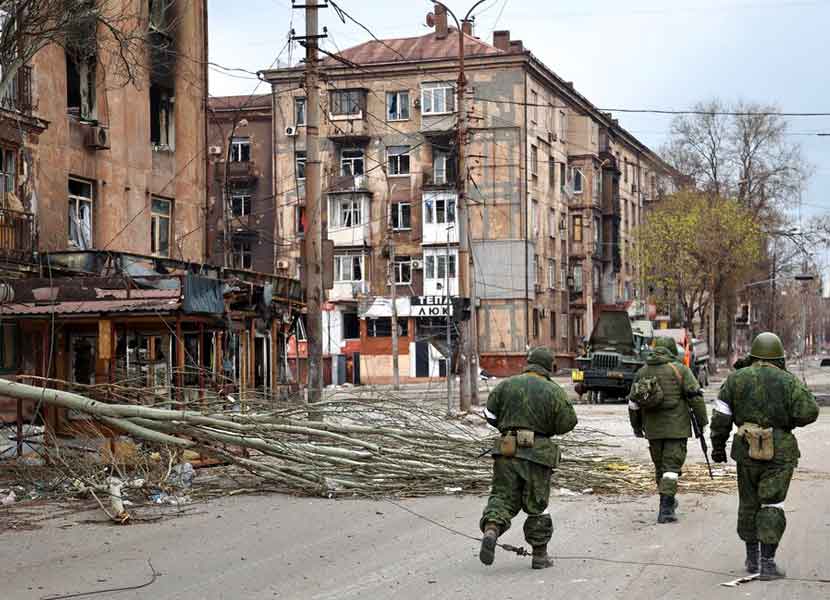 Militares de la milicia de Rusia caminan entre edificios dañados en Ucrania. / Foto: AP