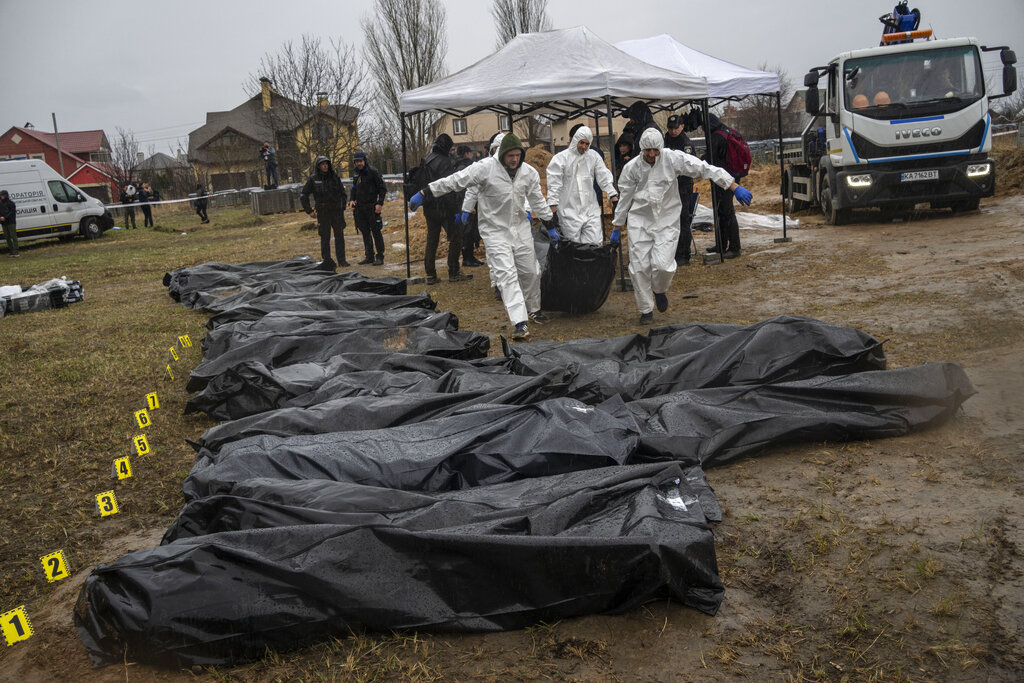 Trabajadores forenses trasladar el cuerpo de un civil asesinado durante la guerra con Rusia tras sacarlo de una fosa común en Kiev, Ucrania, el 8 de abril de 2022. (AP)