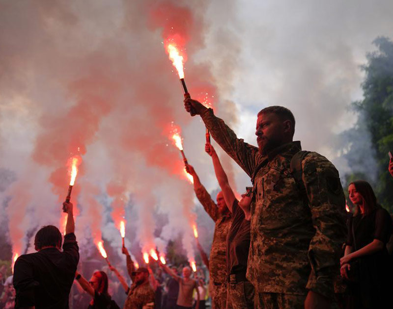 Los soldados sostienen bengalas mientras asisten al funeral del activista y soldado Roman Ratushnyi en Kyiv, Ucrania. / Foto: AP
